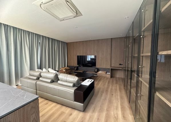 Lounge with a sofa and television, with glass cabinets to the right of them